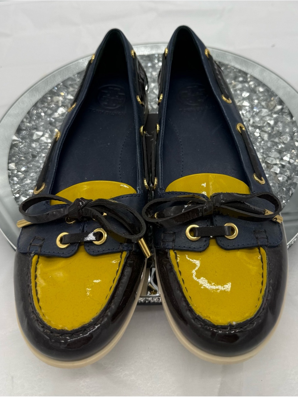 Tory Burch patent leather boat shoes in navy blue and yellow.